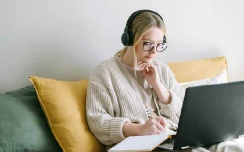 woman on her couch with a laptop looking for best business ideas for women at home. Check out these 18 business ideas for women from home